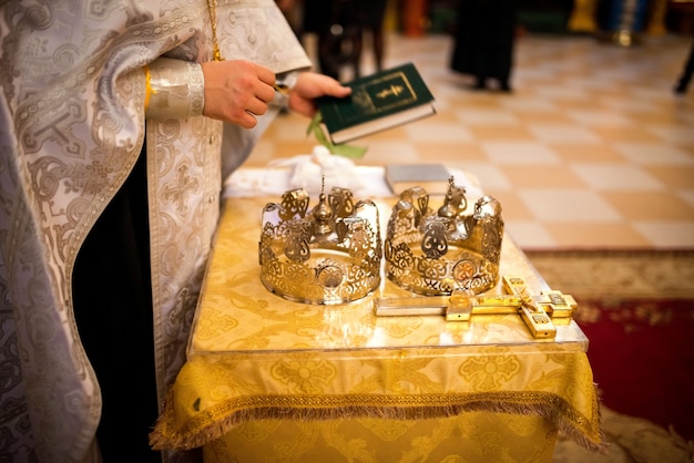 Concept de cérémonie de mariage à l'église. Anneaux d'or sur l'assiette. Arrière-plan flou. Fermer.