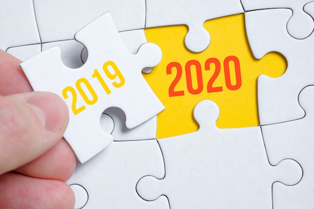 Le concept de changer l'année de 2019 à 2020. Une pièce du puzzle est tenue par un homme avec ses doigts