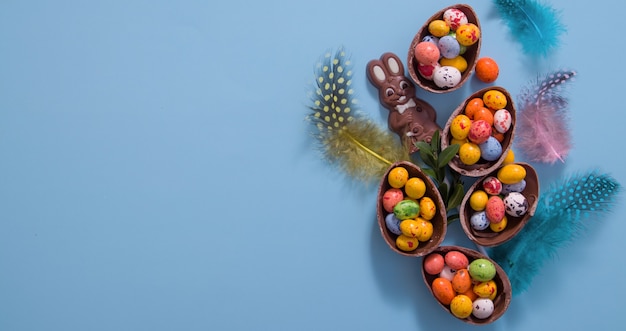 Concept De Chasse Aux Oeufs De Bannière De Pâques Avec Des Oeufs En Chocolat à Plat Et Lapin Sur Fond Bleu. Vue D'en-haut