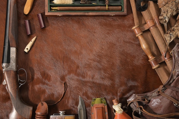 Photo concept de chasse avec un couteau de fusil de chasse et des munitions de chasse disposés sur un fond brun chasse à la volaille sauvage