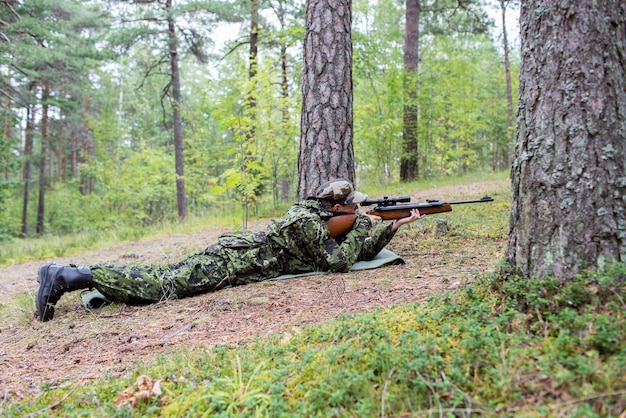 concept de chasse, de guerre, d'armée et de peuple - jeune soldat, ranger ou chasseur avec arme à feu dans la forêt