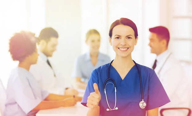 concept de clinique, de profession, de personnes et de médecine - femme médecin heureuse sur un groupe de médecins réunis à l'hôpital montrant le geste du pouce levé