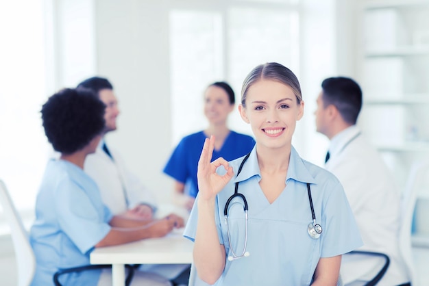 concept de clinique, de profession, de personnes et de médecine - femme médecin heureuse sur un groupe de médecins réunis à l'hôpital montrant le signe de la main ok