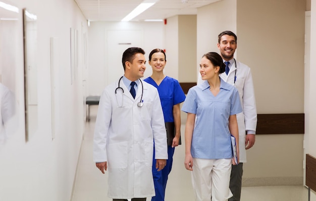concept de clinique, de profession, de personnes, de soins de santé et de médecine - groupe de médecins ou de médecins heureux marchant le long du couloir de l'hôpital