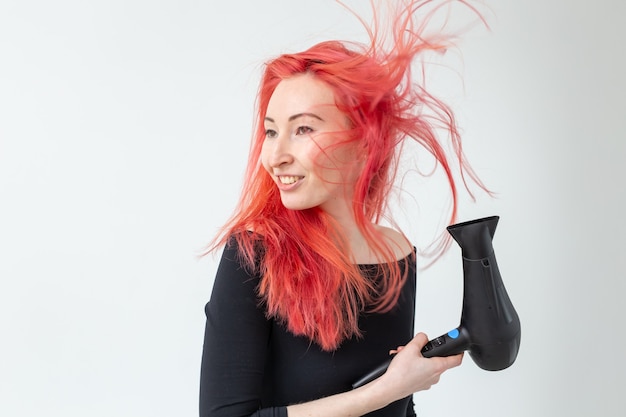 Concept de coiffeur, de salon de beauté et de personnes - coiffeur jeune femme avec sèche-cheveux sur fond blanc.