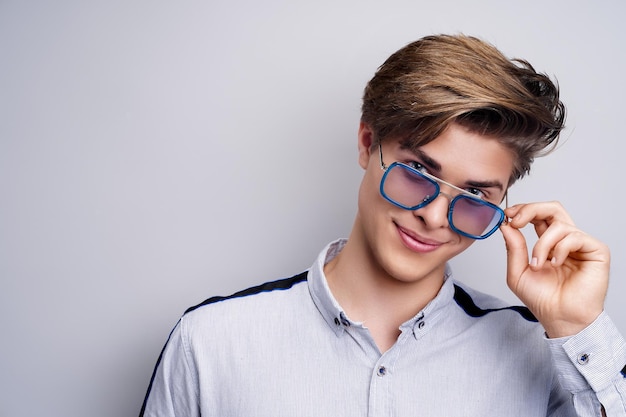 Concept de coiffure masculine hipster homme souriant avec une coupe de cheveux élégante dans des verres sur fond blanc