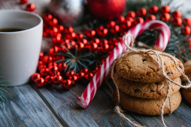 Concept de collation de nourriture festive de Noël. tas de biscuits aux pépites de chocolat et une tasse de thé sur fond de bois. décoration saisonnière de chaîne de perles rouges en toile de fond.