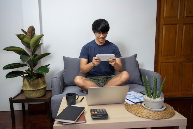 Concept de commerce électronique un adulte de sexe masculin regardant un film de la tablette blanche assis sur le canapé gris