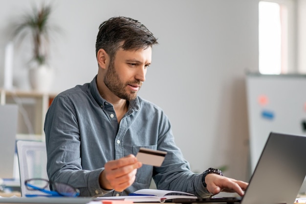 Concept de commerce électronique homme d'affaires mature utilisant une carte de crédit et un ordinateur portable faisant des achats en ligne assis