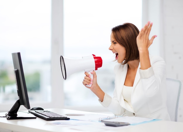 concept commercial et technologique - femme d'affaires stricte criant dans un mégaphone au bureau