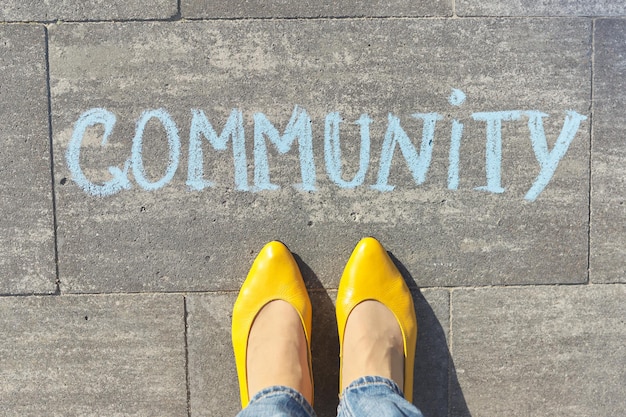 Concept communautaire, vue de dessus sur les jambes de la femme et texte écrit à la craie sur le trottoir gris.