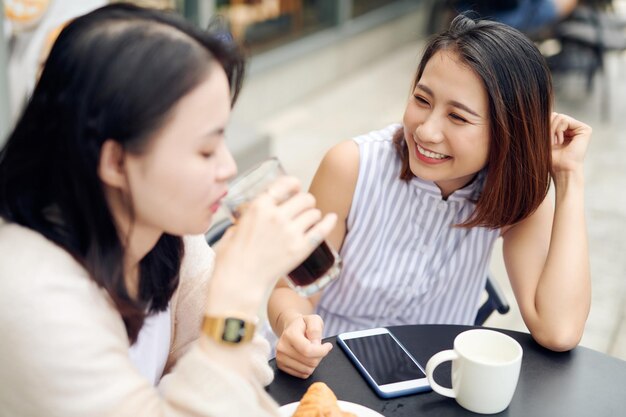 Concept de communication et d'amitié entre les gens souriant jeunes femmes buvant du café et parlant au café en plein air