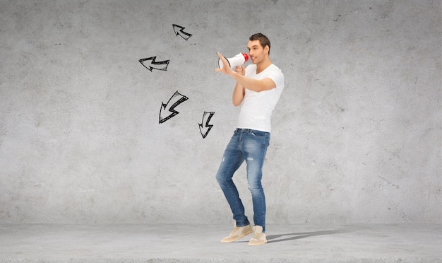 concept de communication - bel homme avec mégaphone sur mur de béton