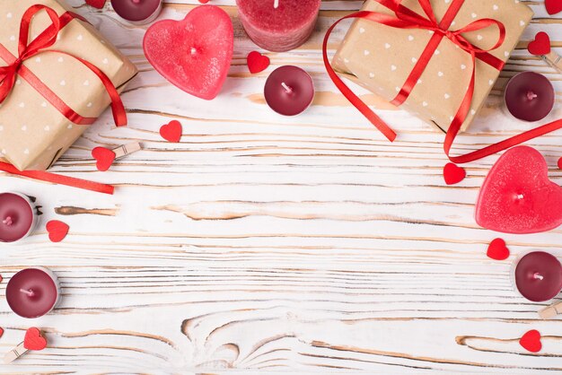 Concept de composition de la Saint-Valentin. Au-dessus des frais généraux vue rapprochée photo de boîtes à cadeaux bougies et jolis coeurs sur table en bois blanc