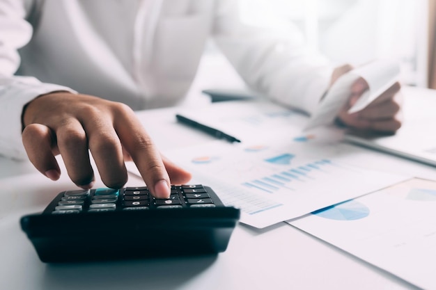 Concept de comptabilité d'entreprise Homme d'affaires à l'aide d'une calculatrice avec budget d'ordinateur portable et papier de prêt au bureau