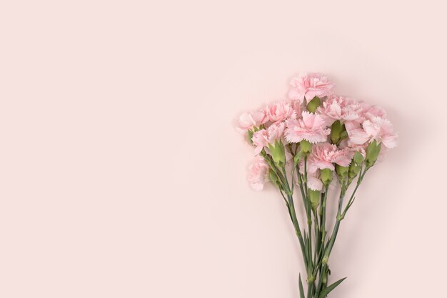 Concept de conception de la conception de voeux de vacances de fête des mères avec bouquet d'oeillets sur fond de table rose pastel