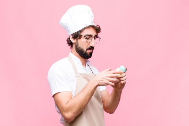 Concept de confiserie jeune boulanger fou contre mur rose