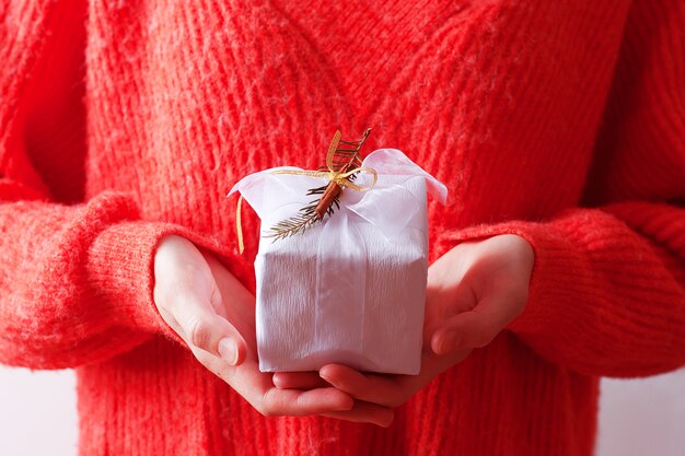 Photo concept confortable de noël avec femme en pull tenant un cadeau artisanal