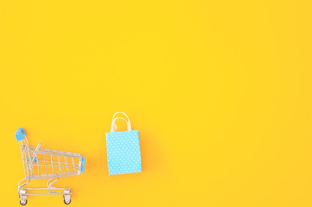 Concept de consommation minimalisme Mini caddie pour faire du shopping sur la vue de dessus de fond de couleur