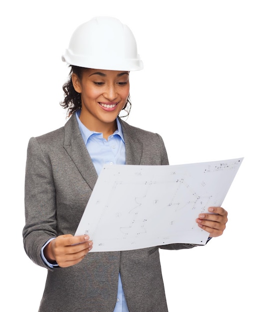 concept de construction, de développement, de construction et d'architecture - femme d'affaires souriante en casque blanc regardant le plan