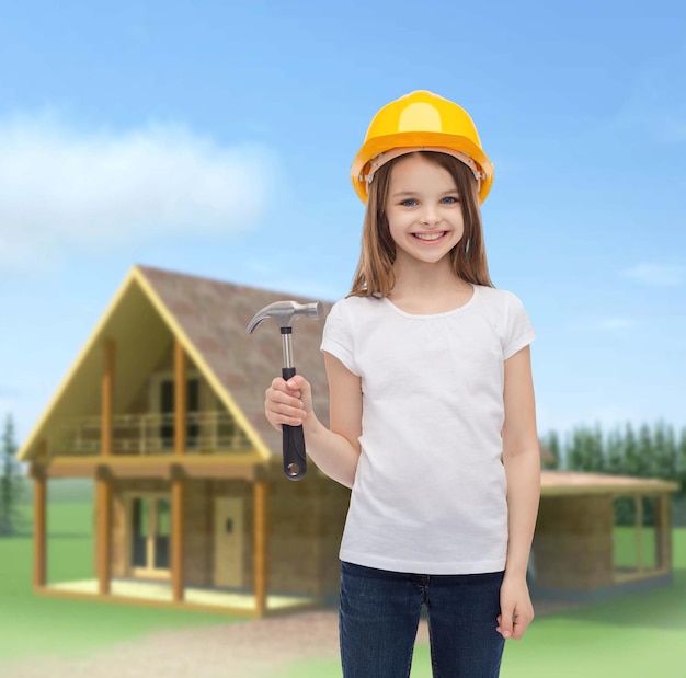 concept de construction et de personnes - petite fille souriante dans un casque de protection avec marteau