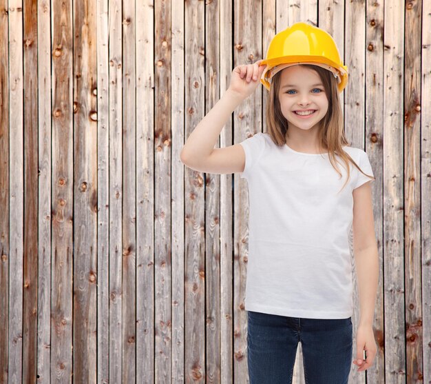 concept de construction et de personnes - petite fille souriante dans un casque de protection