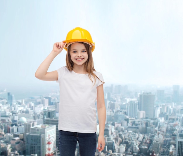 concept de construction et de personnes - petite fille souriante dans un casque de protection