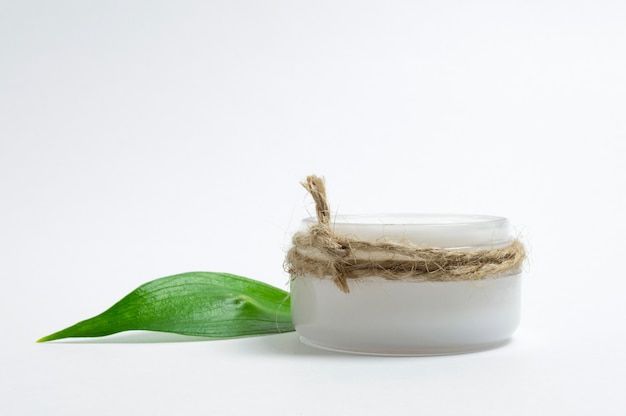 Concept de cosmétiques naturels. Pot cosmétique avec crème pour le visage et feuille verte. Fond blanc.