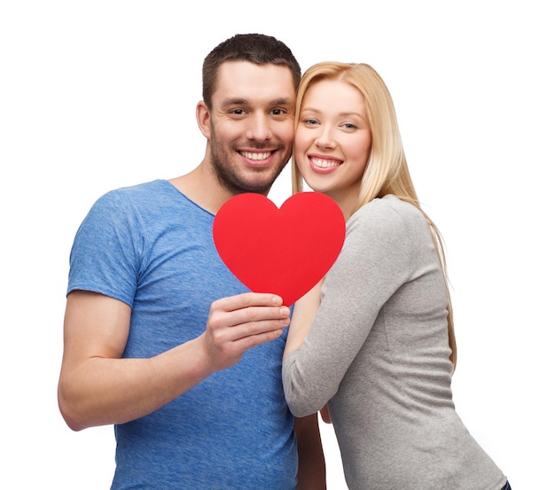 concept de couple, d'amour et de famille - couple souriant tenant un grand coeur rouge