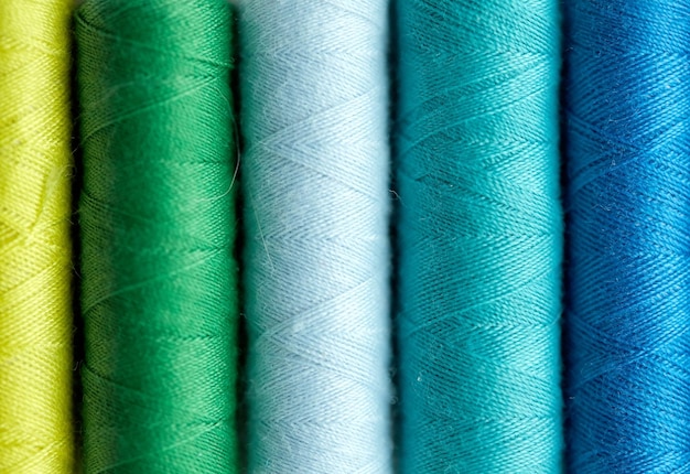 Photo concept de couture, d'artisanat, de couture et de couture - rangée de bobines de fil colorées sur table