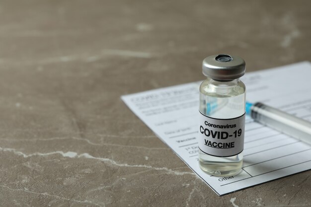 Concept de Covid - 19 vaccination avec vaccin et seringue sur fond texturé gris