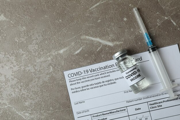 Concept de Covid - 19 vaccination avec vaccin et seringue sur tableau texturé gris