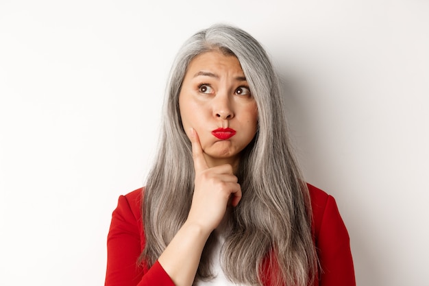 Concept de Covid, pandémie et entreprise. Femme d'affaires en blazer rouge et masque facial à l'aide d'un désinfectant pour les mains pour nettoyer et désinfecter, debout sur fond blanc.