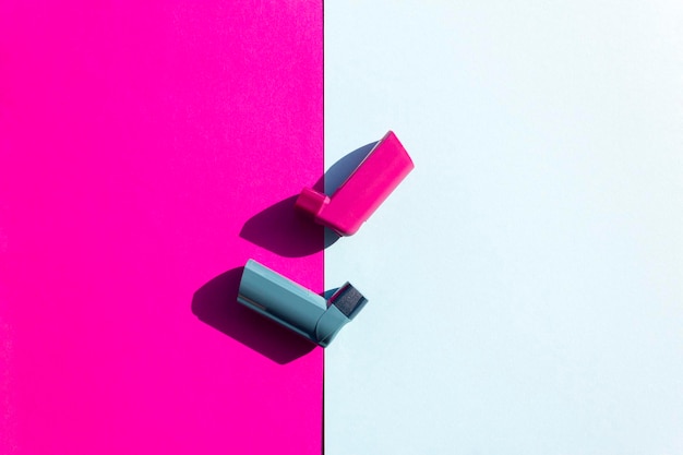 Photo concept créatif d'asthme inhalateurs d'asthme bleus et roses sur fond bleu et rose plat