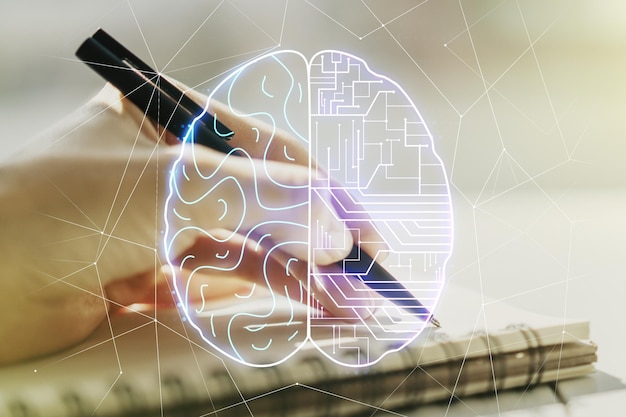 Concept créatif d'intelligence artificielle avec hologramme du cerveau humain et main de femme écrivant dans un cahier sur fond