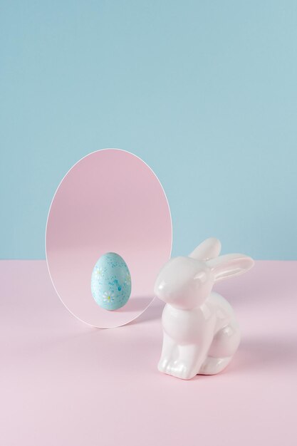 Concept créatif avec lapin de Pâques et oeuf dans un miroir sur une table rose pastel Idée minimale de vacances de Pâques