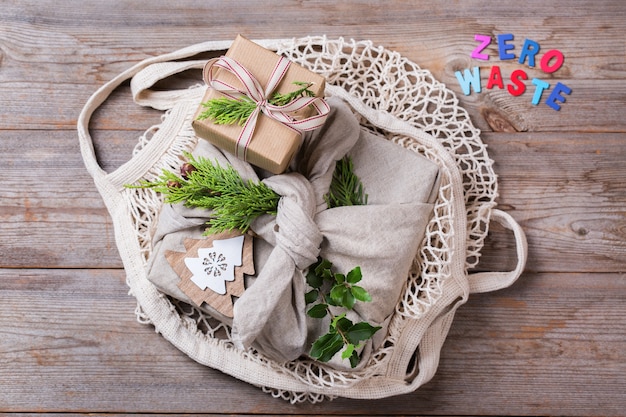 Concept créatif de Noël zéro déchet. Coffrets cadeaux avec du papier d'emballage artisanal écologique fait à la main et un emballage en tissu furoshiki de style japonais traditionnel dans un sac en filet. Fond de vue de dessus plat