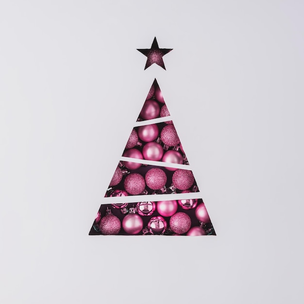 Concept créatif pour Noël et la nouvelle année Arbre de Noël en forme de triangle avec des boules d'arbre de Noël roses sur fond gris