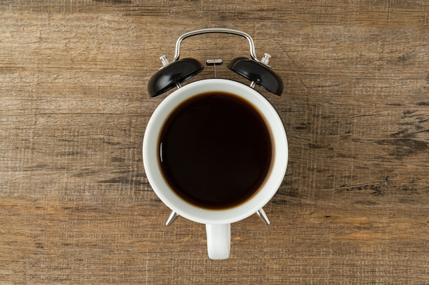 Concept créatif une tasse de café et réveil vintage noir sur fond de bois