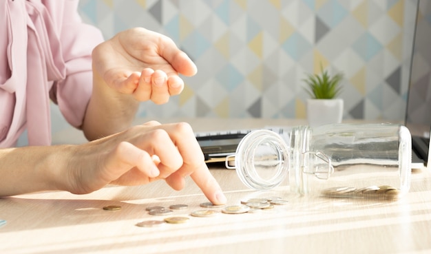 Le concept de crise et économiser de l'argent - la jeune fille compte des pièces sur la table au bureau