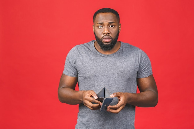 Concept de crise de pauvreté. Bouleversé jeune homme barbu afro-américain en tenue décontractée portefeuille vide