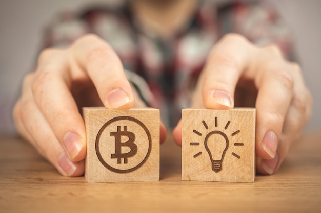 Concept de croissance bitcoin Idée d'ampoule et symboles BTC sur des cubes en bois dans les mains vue rapprochée Photo d'investissement commercial