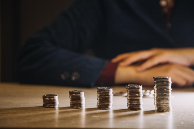 Concept de croissance commerciale financière La main de l'homme met des pièces d'argent dans une pile de pièces