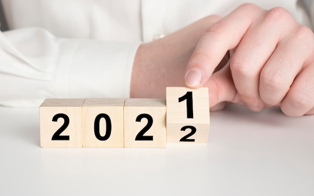 Concept de croissance d'entreprise en 2022 pour le plan d'affaires et la stratégie La main retourne les cubes en bois 2022 et la tendance de croissance sur un beau fond et un espace de copie Bannière pour le nouveau plan d'action plan annuel