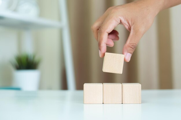 Photo concept de croissance réussie main tenant et empilant blocs de bois cube étape de réussite de croissance d'entreprise