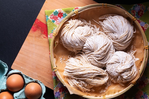 Photo concept de cuisine asiatique nouilles alcalines biologiques fraîches faites maison sur planche de bois avec fond noir avec espace de copie