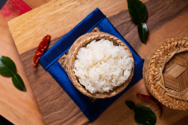 Concept de cuisine asiatique riz gluant ou riz gluant en osier de bambou sur planche de bois et fond noir avec espace de copie