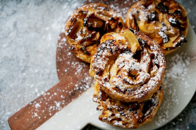 Concept de cuisine à domicile. Tourbillons de pommes au four, tartes, strudel servis sur une planche de marbre décorée de sucre en poudre. Vue de dessus à plat.