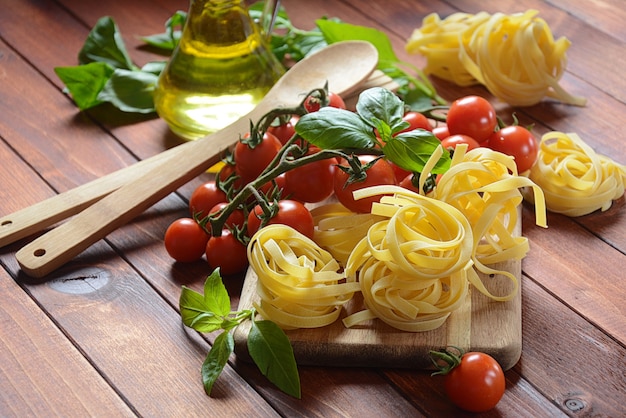 Concept de cuisine italienne avec des pâtes crues, tomate, basilic et huile