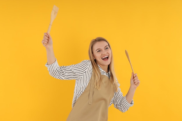 Concept de cuisine avec jeune femme sur fond jaune